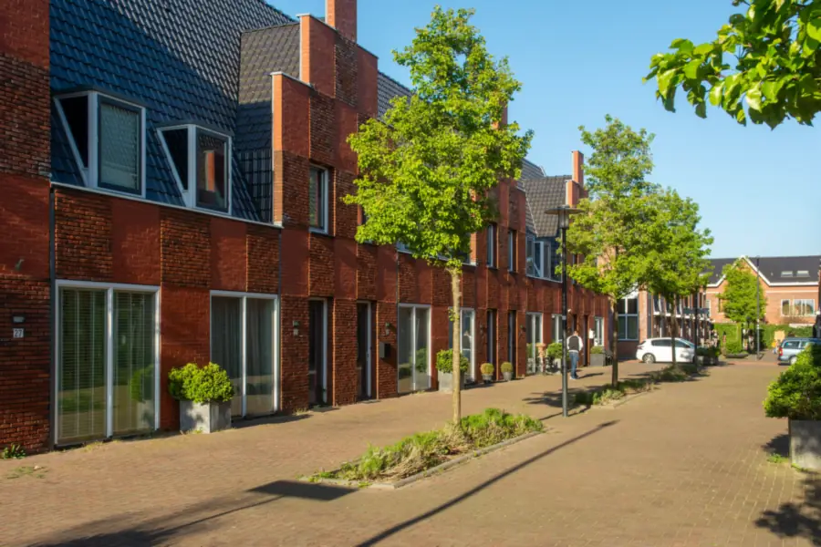 Row of brick family houses on a brick-paved street with young trees, the kind of street where parking on your own plot is regulated