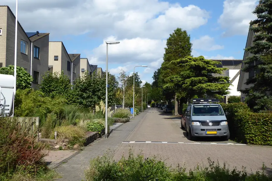 Dutch residential street with brick paving, a pavement and front gardens, where a driveway exit would cross to the road