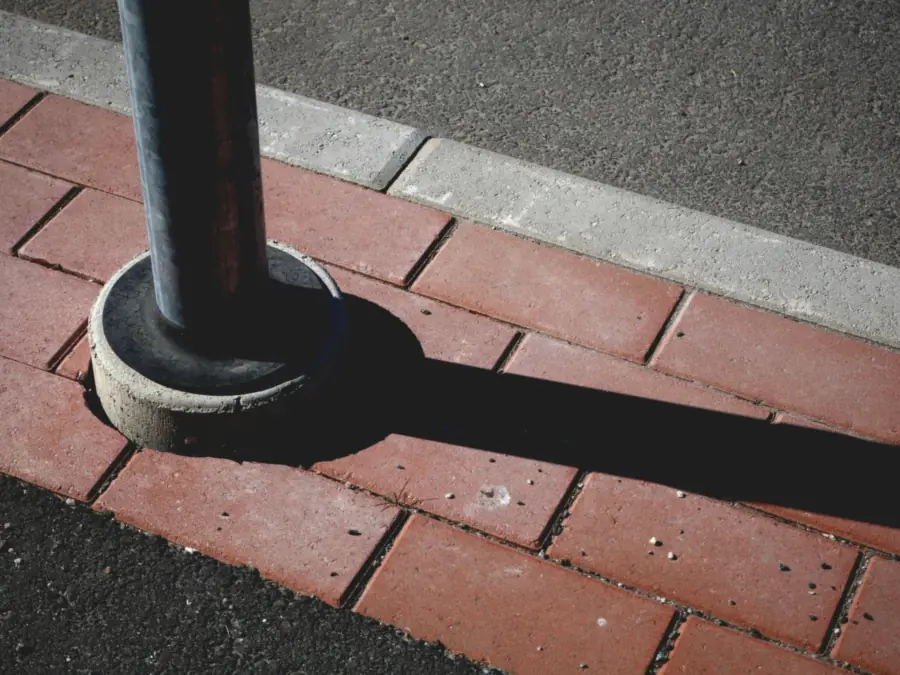 Red concrete pavers held by a grey kerb against asphalt, an edging detail for driveways in Amsterdam